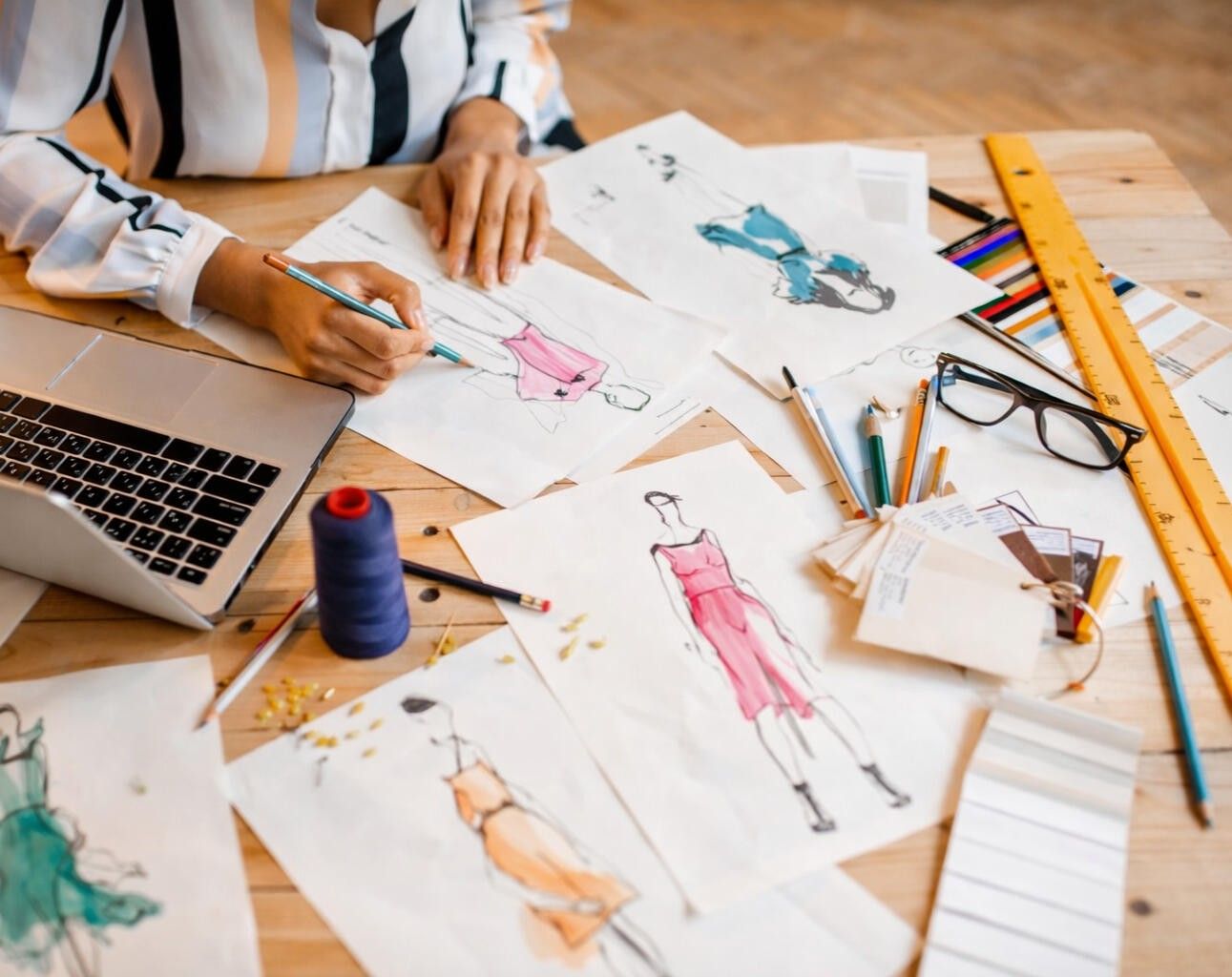 Fashion sketches, fabric swatches and sewing tools on a design desk